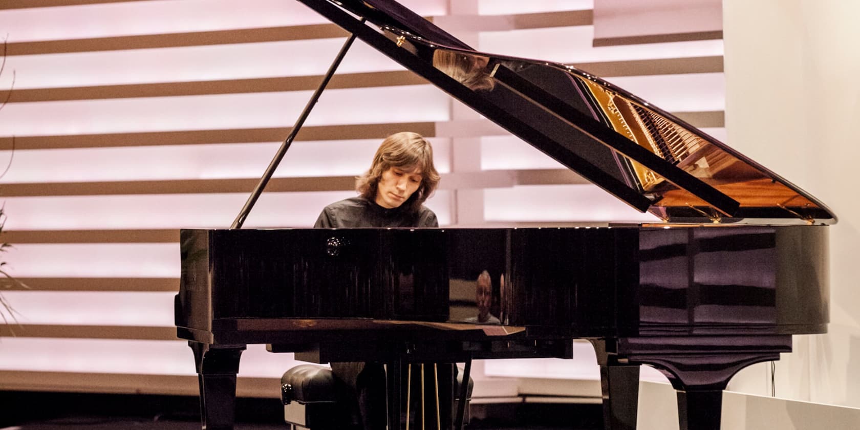 Ein Pianist spielt auf einem großen Flügel in einem modernen Raum.