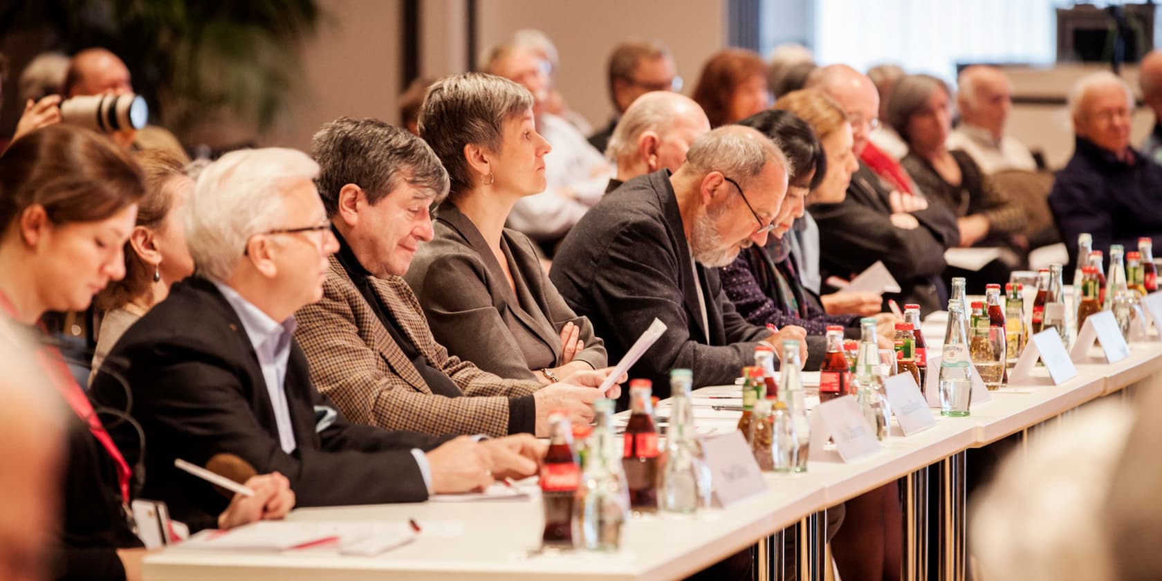 Menschen sitzen an einem Konferenztisch und machen Notizen.
