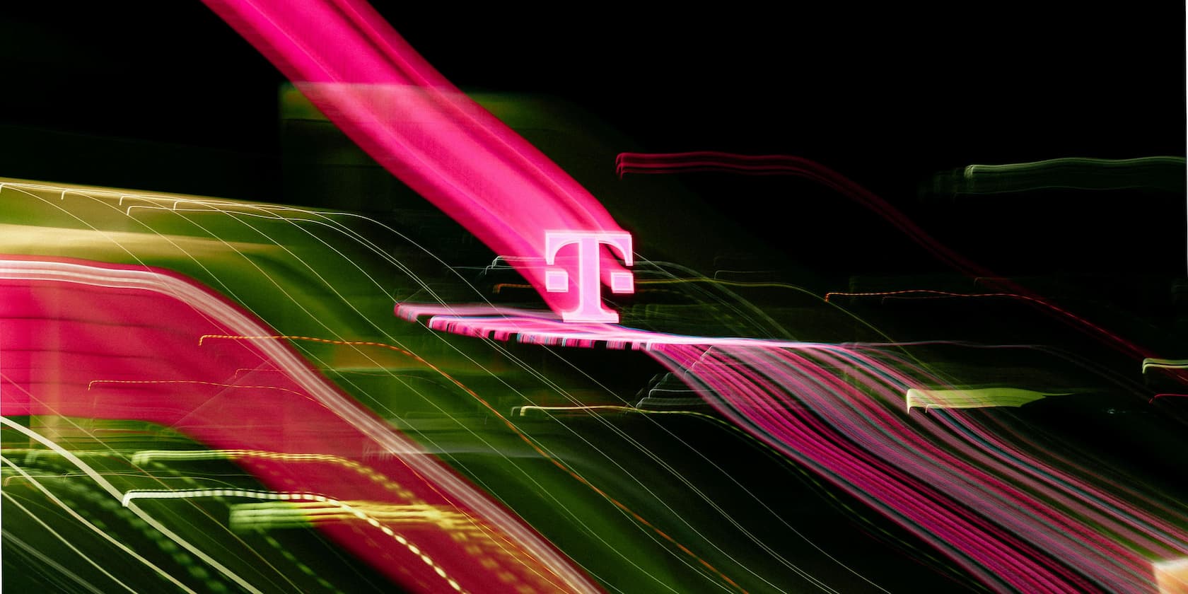Magentafarbenes 'T'-Logo vor buntem, unscharfem Hintergrund