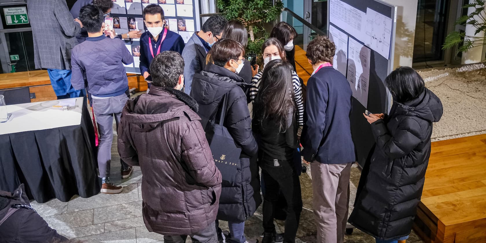 Gruppe von Leuten auf einer Konferenz betrachtet ein Informationsboard.