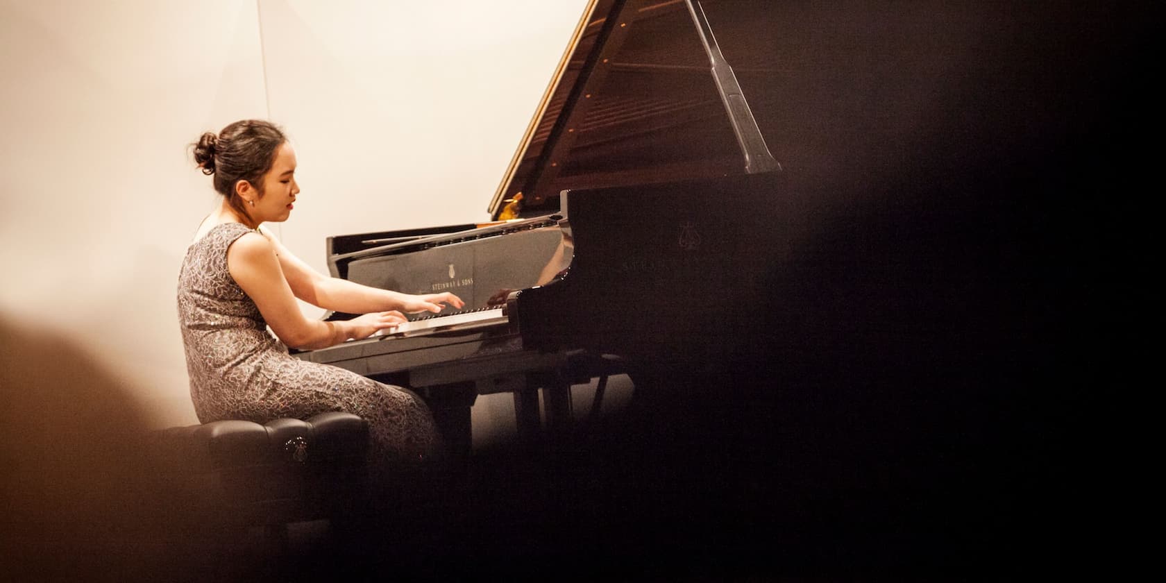 Frau spielt Klavier in einem Konzertsaal
