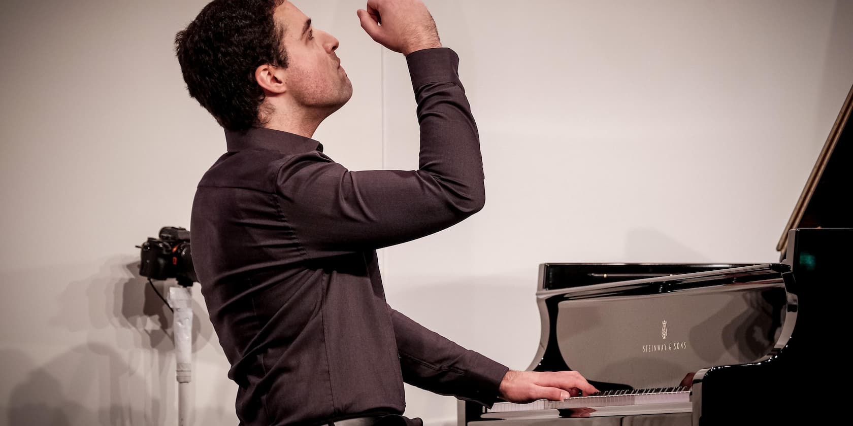 Pianist, der am Klavier spielt und eine dramatische Geste macht.
