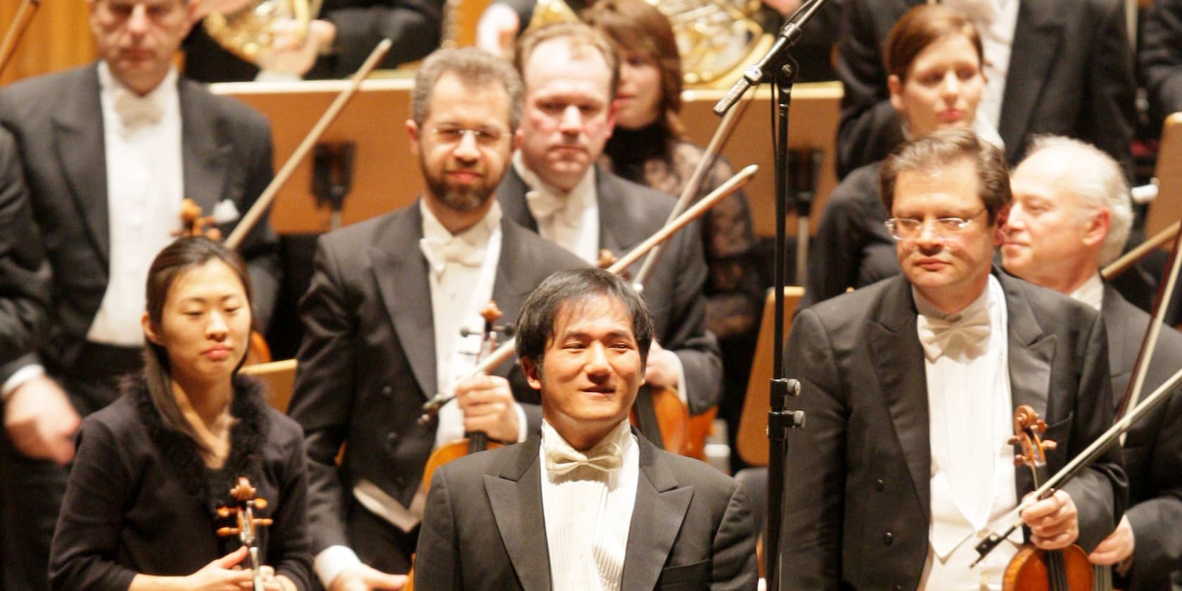 Orchester-Mitglieder in formeller Kleidung auf der Bühne.