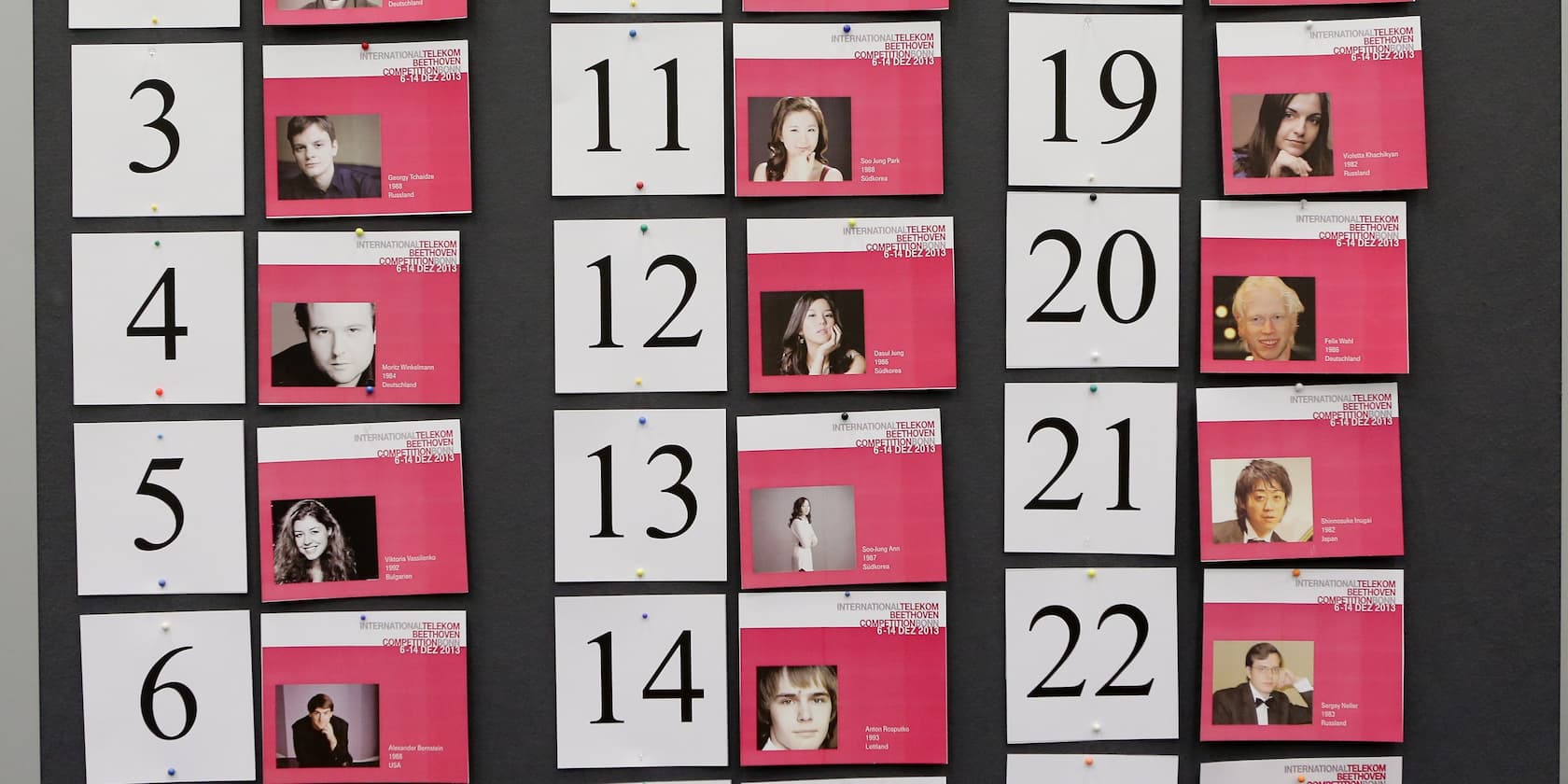 Photos and numbers of participants of the 2013 International Telekom Beethoven Competition are pinned to a wall.