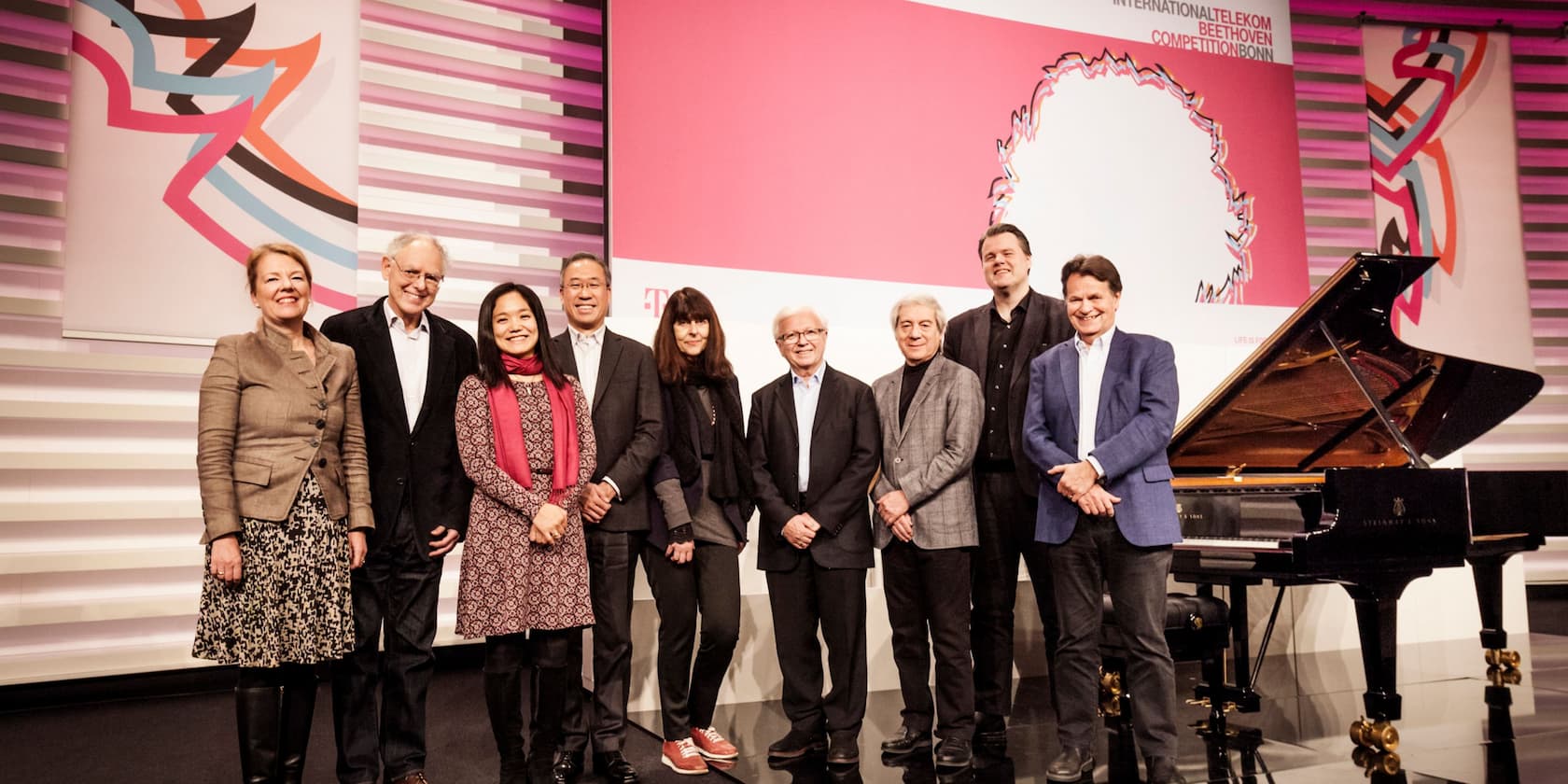 Gruppe von neun Personen steht vor einem Flügel bei der International Telekom Beethoven Competition in Bonn.